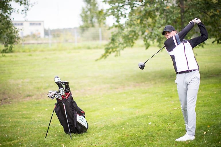 Ung golfare får på en bra träff på fairwayen.