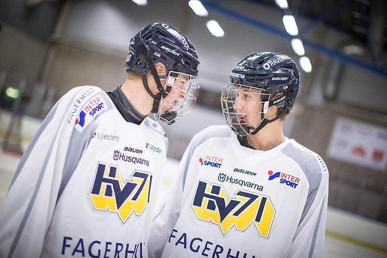 Två hockeyspelare småpratar med varandra genom visiret.